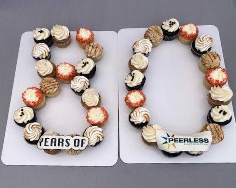 A platter of orange, black, and white cupcakes shaped to form the number 80.