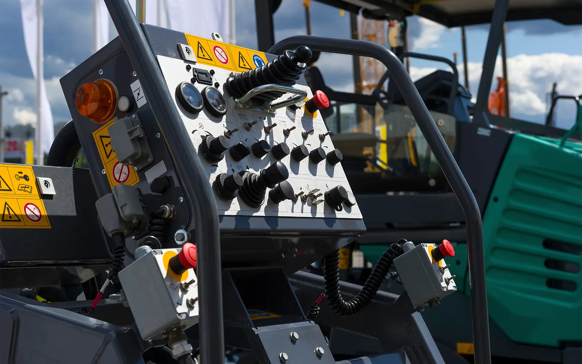 An asphalt paving machine dashboard unit displaying an array of toggle switches, knobs, and more