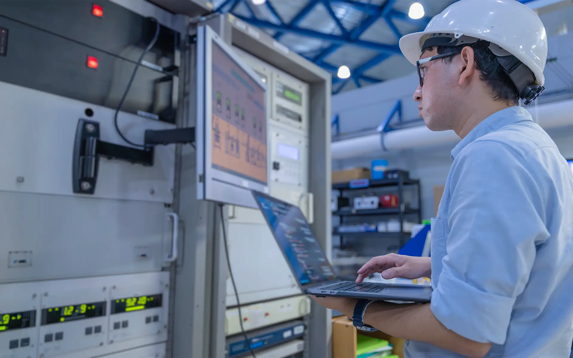 A male electrical engineer checks the monitor of an HMI (human-machine interface) of an industrial control system at an industrial factory