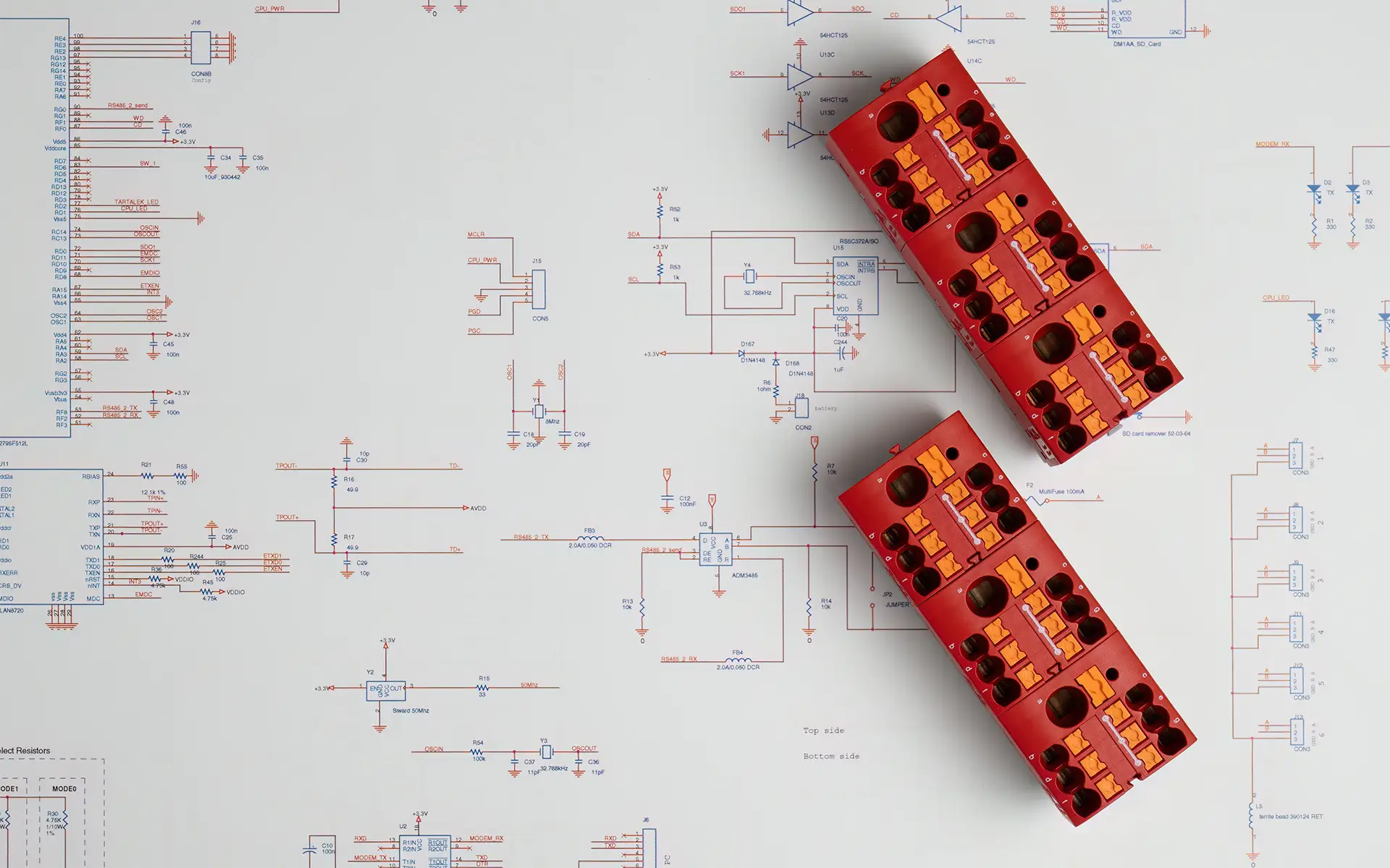 Two red rectangular electrical connectors sitting on top of blueprints